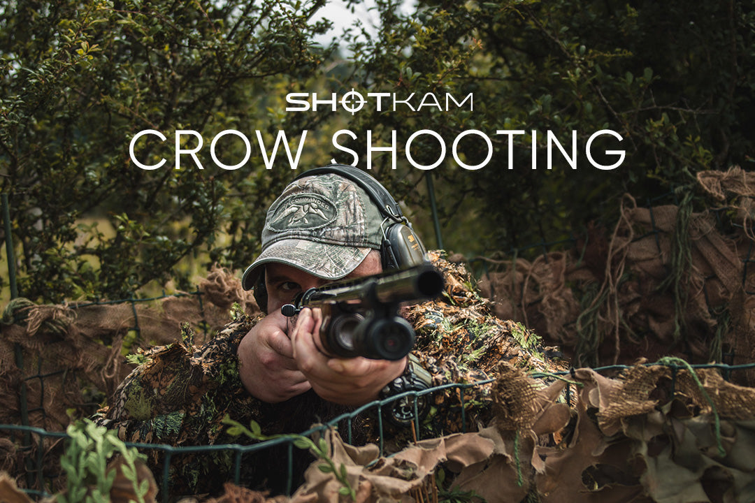 Close-up of a hunter targeting crows with a shotgun, camouflaged and ready to shoot, featuring ShotKam technology.