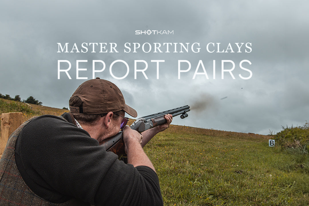 Sporting clays shooter breaking report pairs with visible recoil and ejected shell captured mid-air