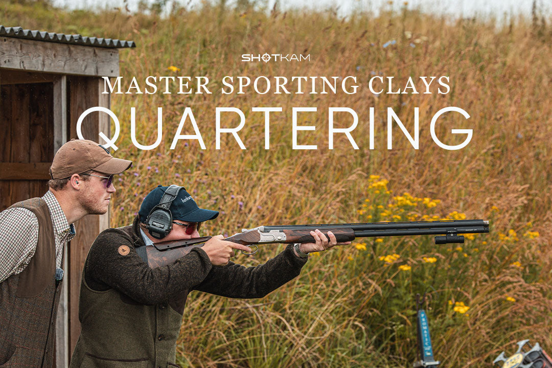 A shooter prepares to tackle quartering targets under the guidance of a coach, with a ShotKam camera visible on the shotgun.